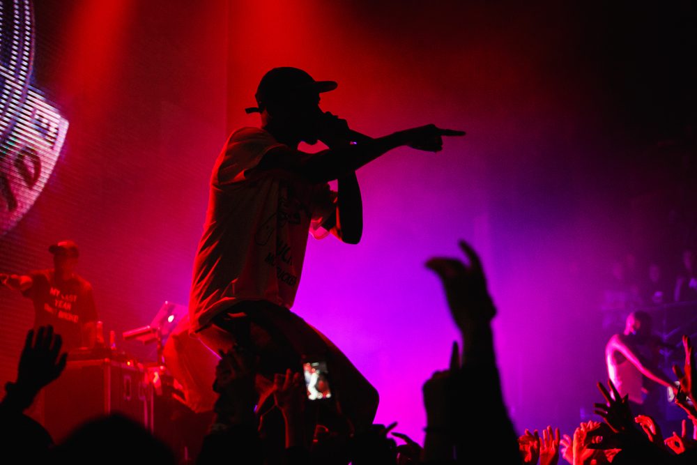 Rapper on stage pointing into the crowd under red and violet lights